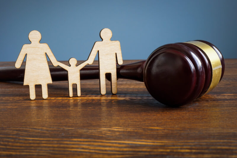 2D wooden cutout of family sits on a table next to a justice gavel. Contact our Boise, ID family law lawyer to make sure you have strong legal support for difficult family legal matters.