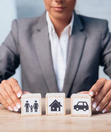 Woman touching wooden cubes with images of a family, a car, and a house. Take out the stress of dividing assets after a divorce and contact our experienced high asset divorce attorneys for legal support.