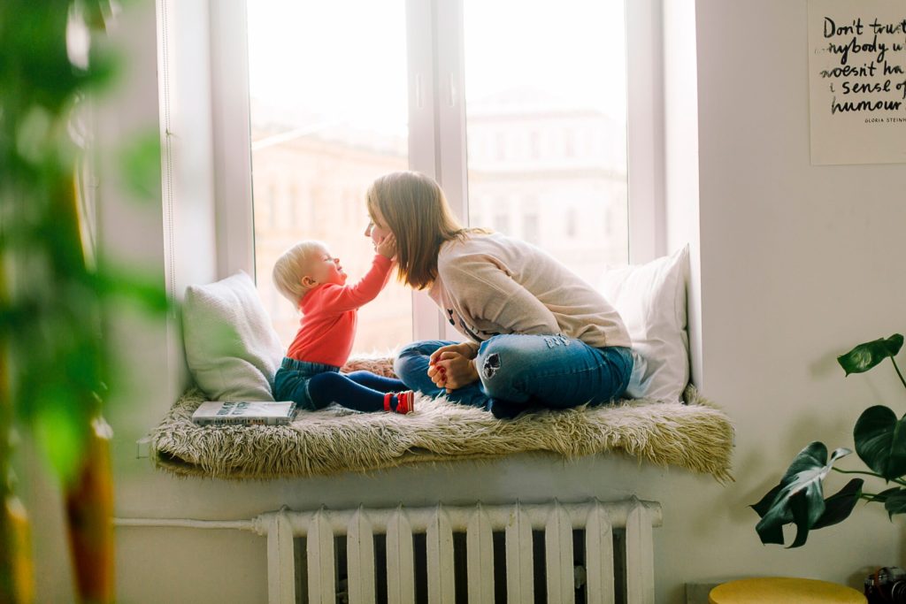 Happy baby touches mother’s face in front of window. Protect you and your child’s future with an experienced Meridian child custody attorney. Call us now.