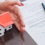 Cropped view of female hands near house model, paper with bankru
