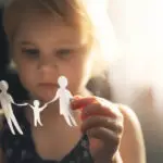 little girl with paper family in hands. concept of divorce, custody and child abuse